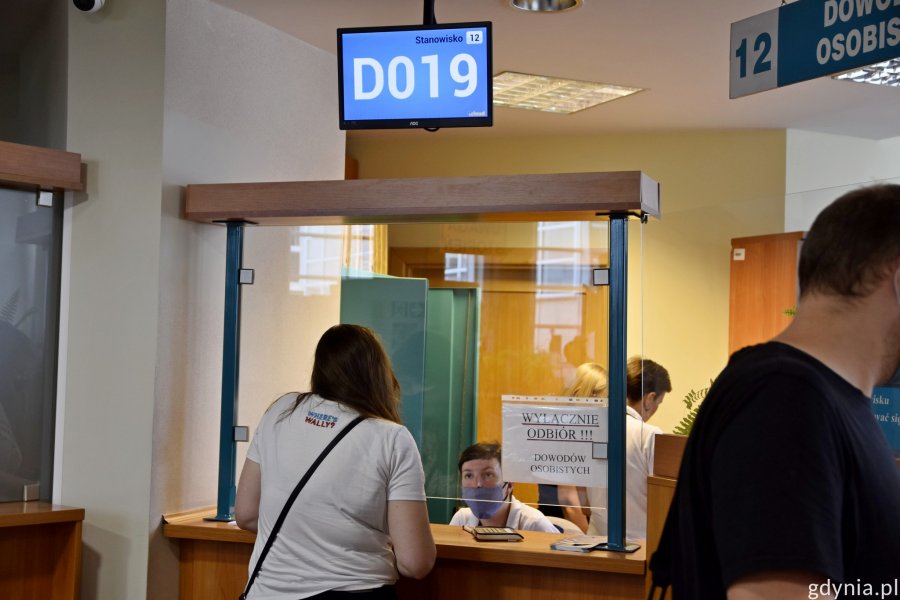 Mieszkańcy mogą odebrać m.in. dowody osobiste bez wcześniejszej rezerwacji wizyty. Na zdjęciu mieszkańcy stojący przy stanowiskach odbioru dowodów osobistych. Nad okienkiem wyświetlają się numery // fot. Paweł Kukla