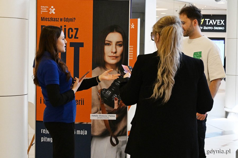 Galeria handlowa „Klif”: baner z napisem Rozlicz PIT w Gdyni i wygraj w loterii, obok konsultantka rozmawia z kobietą i mężczyzną
