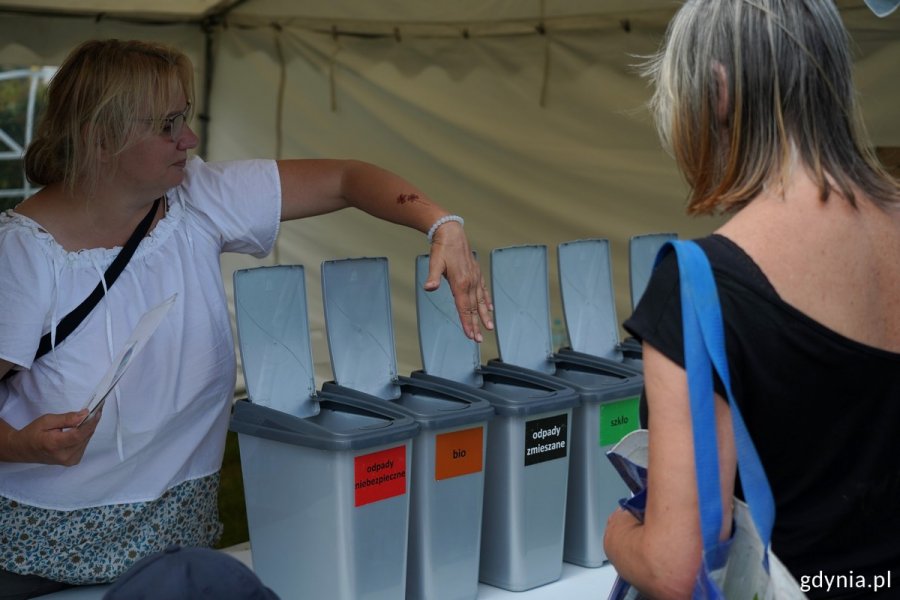 Kobieta tłumaczy innej, jak segregować śmieci