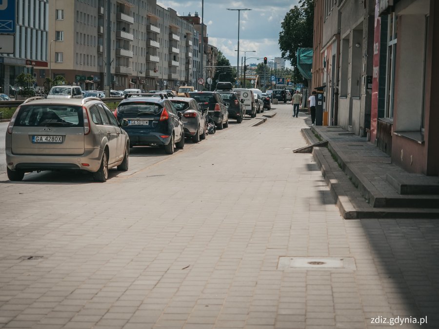 Chodnik na ul. Śląskiej po remoncie, widoczne budynki, samochody, oznakowanie