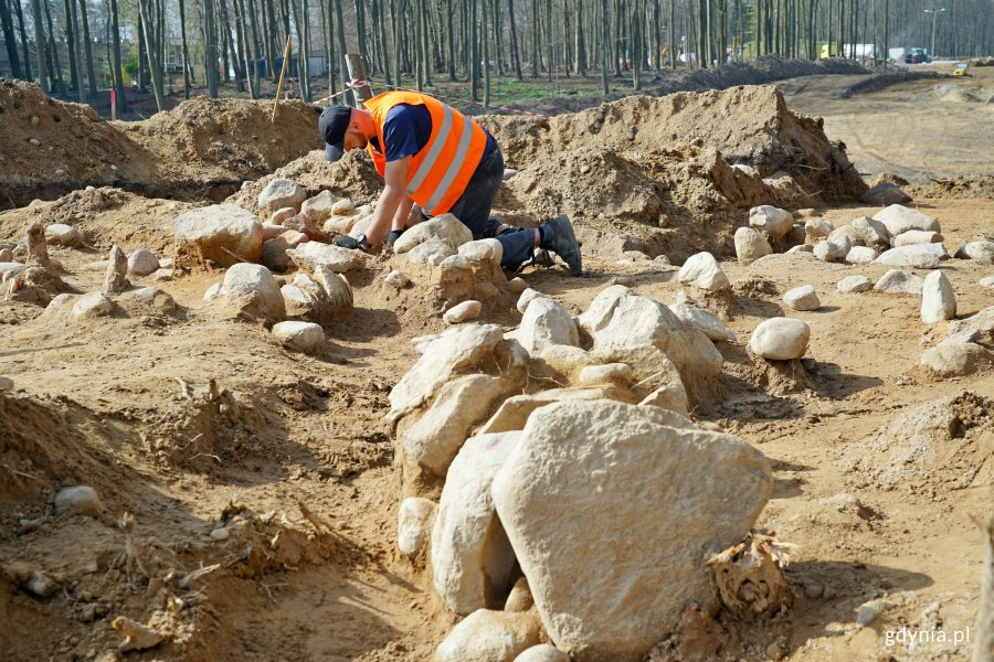 Archeolog w odblaskowej kamizelce pracujący w miejscu, gdzie znaleziono kurhany