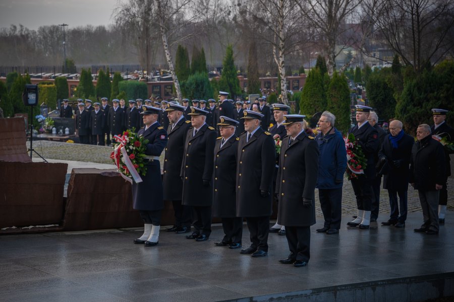 Oficerowie Marynarki Wojennej stoją z wieńcami