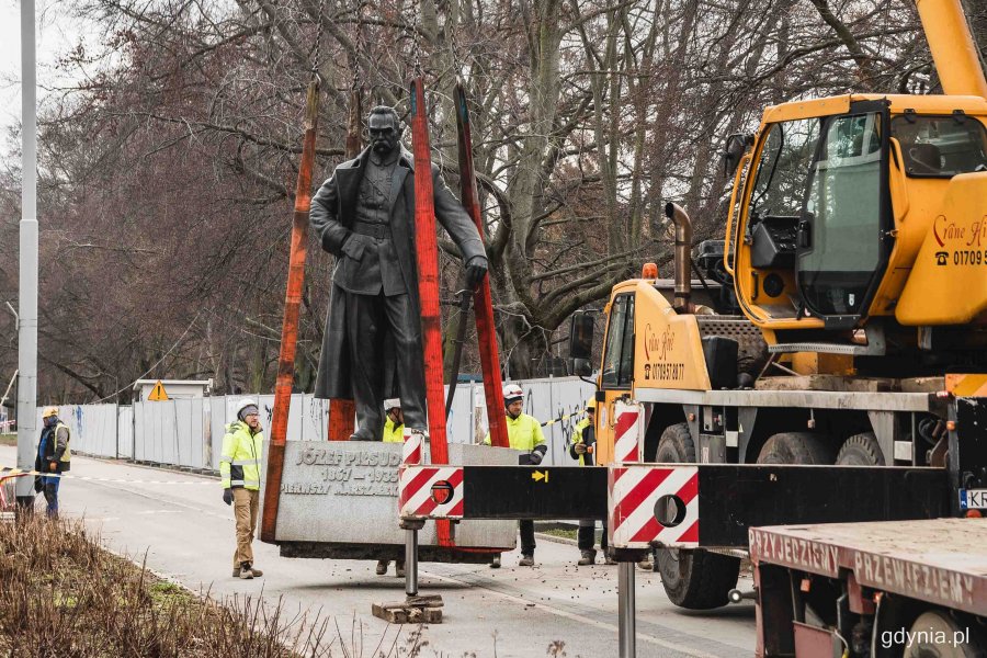 Pomnik Józefa Piłsudskiego uniesiony na czerwonych taśmach na dźwigu w drodze na dawne miejsce przy skwerze Plymouth i Urzędzie Miasta Gdyni // fot. Kamil Złoch