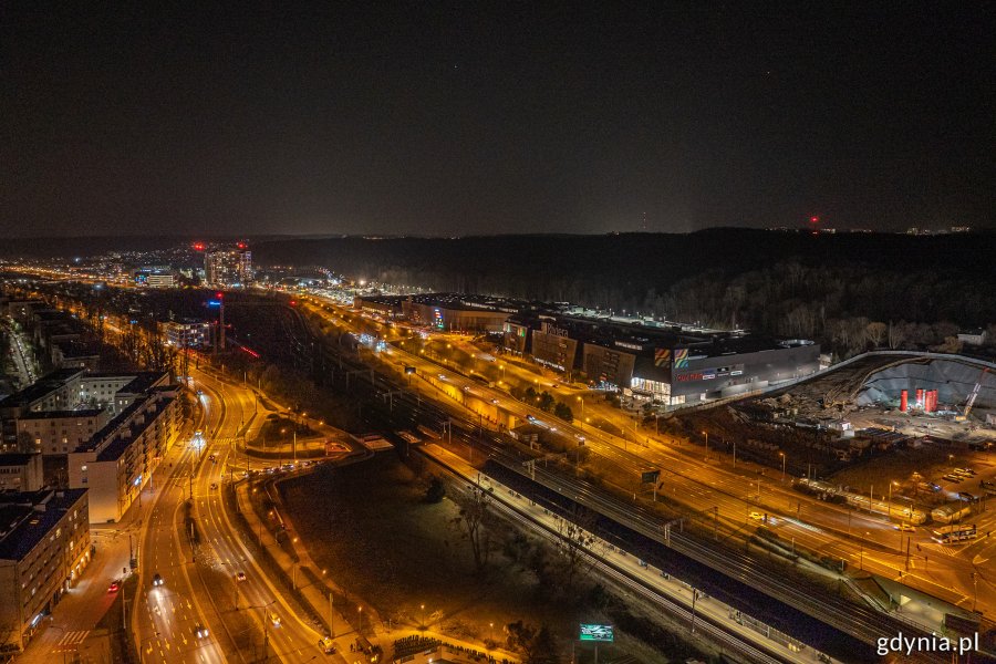 Nocne zdjęcie budynków, w których są zgaszone światła, stojących przy oświetlonych ulicach