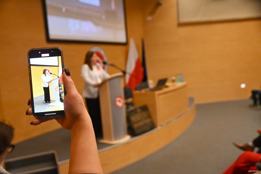 Ręka z telefonem nagrywająca wystąpienie prezydent