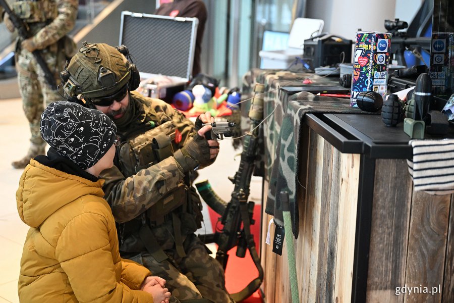 Strefa z wojskiem i militariami w Centrum Riviera. Żołnierz w mundurze pokazuje sprzęt wojskowy dziecku