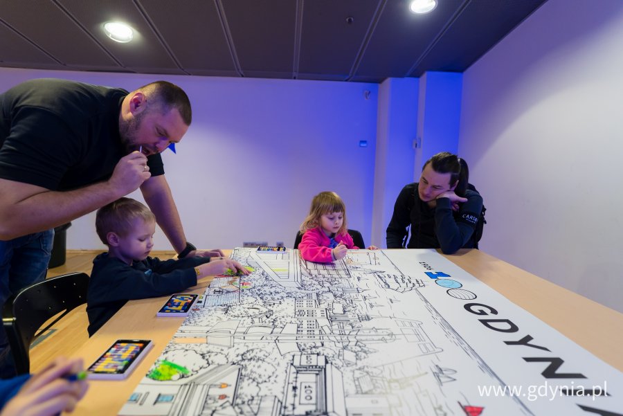 Dzieci i dorośli pochyleni nad kolorowanką o Gdyni