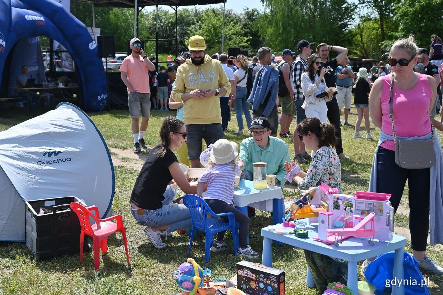 Mieszkańcy na pikniku rodzinnym przy stolikach w wyprzedażą sąsiedzką