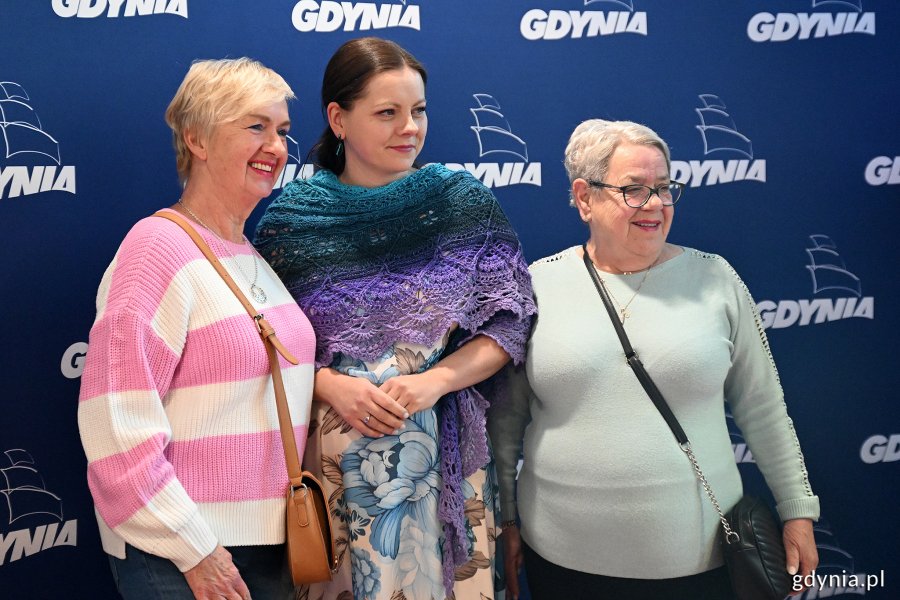 Dwie seniorki i Aleksandra Kosiorek pozują do zdjęcia, w tle logotypy Gdyni