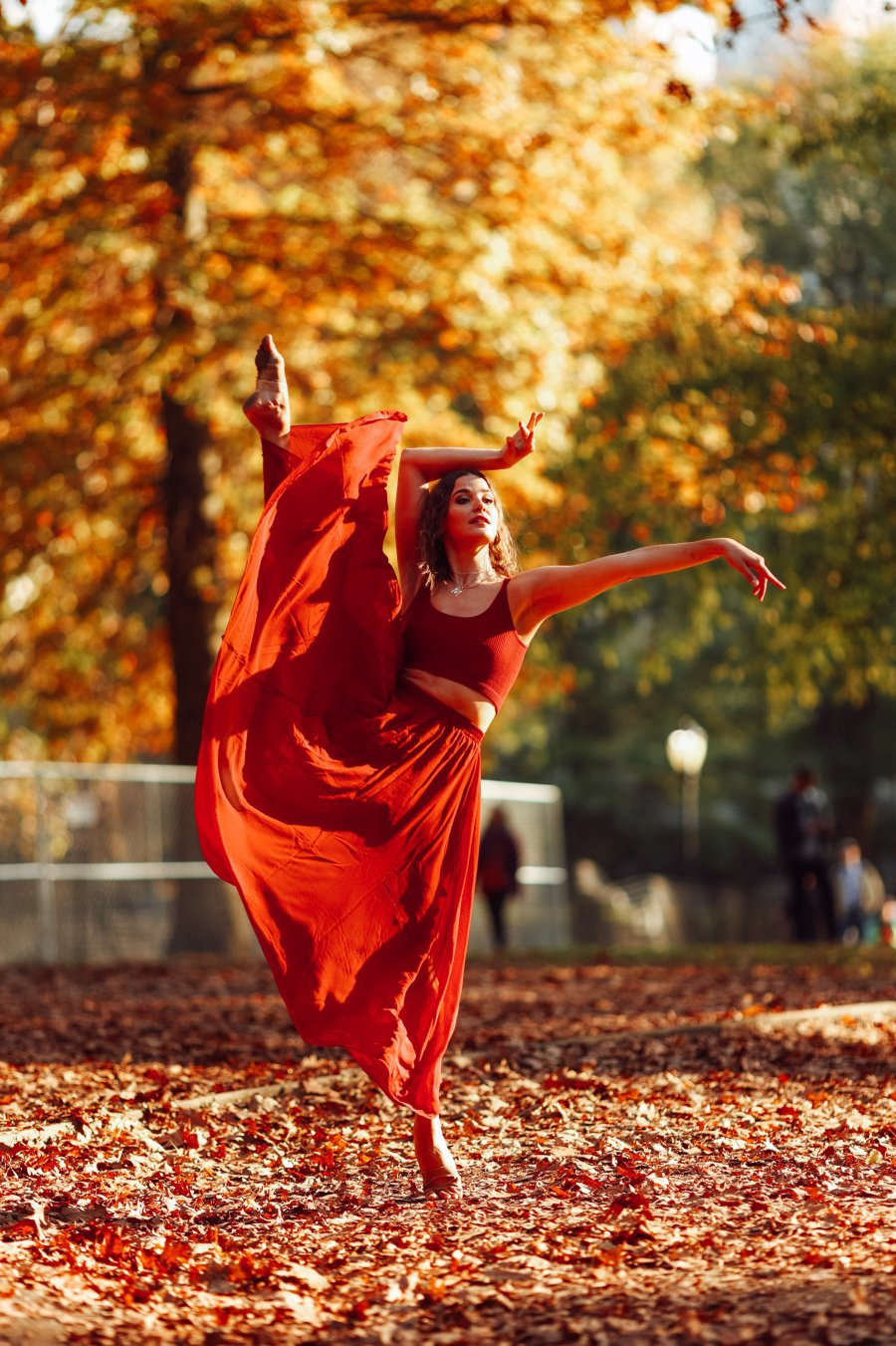 Tancerka w czerwonej sukni, w tle jesienna sceneria