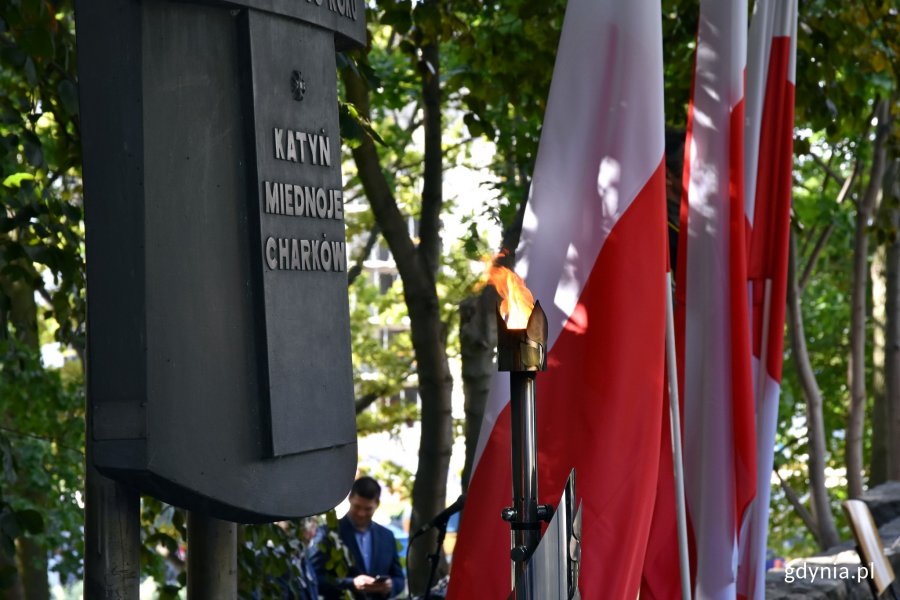 Pomnik Ofiar Katynia przed którym płonie znicz. ?W tle biało-czerwone flagi // fot. Magdalena Czernek