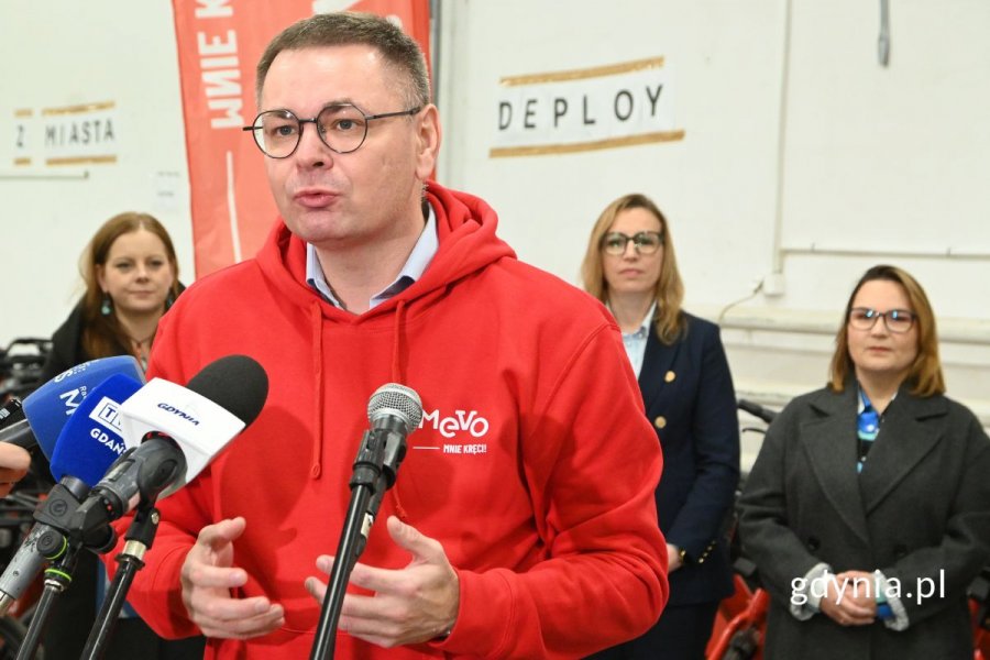 Mężczyzna mówiący do kilku ustawionych obok siebie mikrofonów