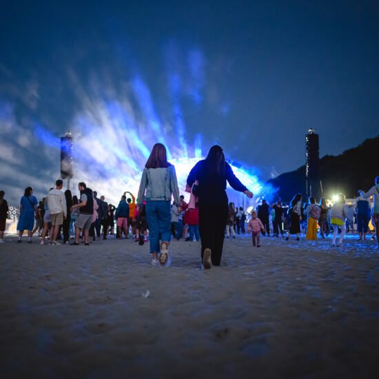 Festiwal Cudawianki. Dwie kobiety idące w kierunku sceny podczas koncertu na plaży