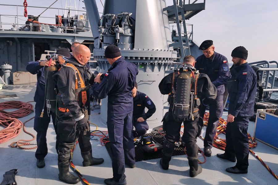 Nurkowie przygotowują się do akcji pod wodą podczas ćwiczeń taktycznych na Bałtyku. Zakładają sprzęt i odzież ochronną, a pomagają im w tym marynarze z załogo okrętu // fot. archiwum dOW