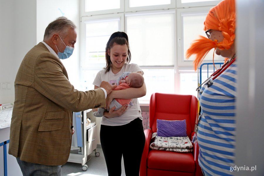 W pokoju szpitalnym stoi prezydent Gdyni, kobieta przebrana za Pippi oraz mama z małym dzieckiem na rękach.