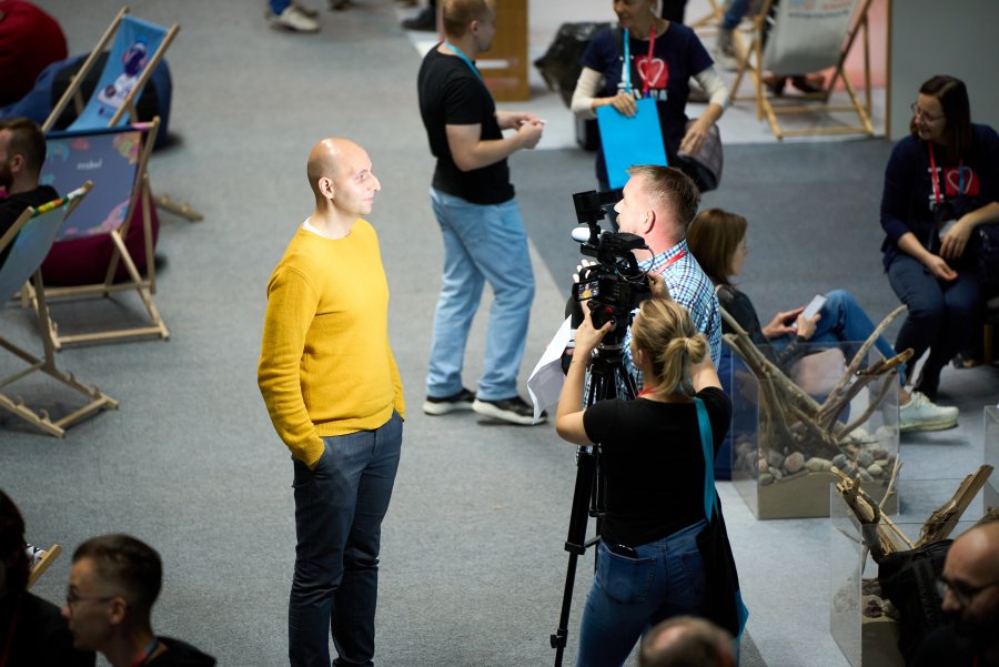 Widziana z góry ekipa filmowa z kamerą nagrywająca stojącego mężczyznę