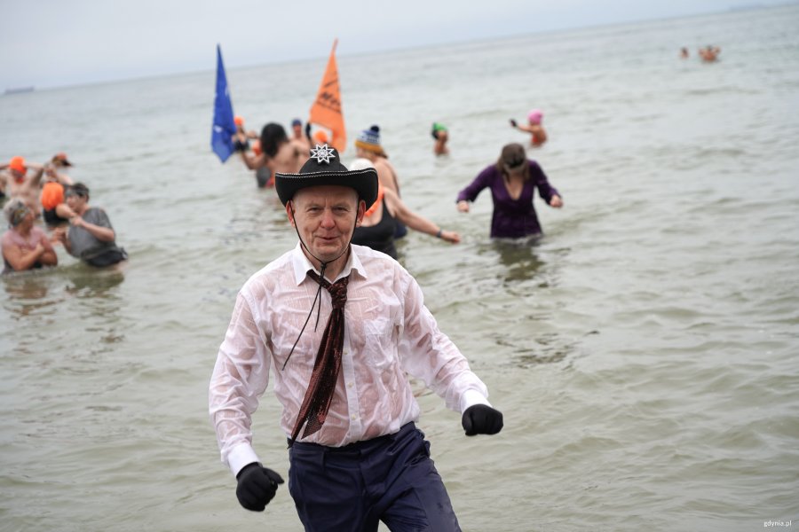 Mężczyzna z białej koszuli i kowboiskim kapeluszu wychodzi z morza