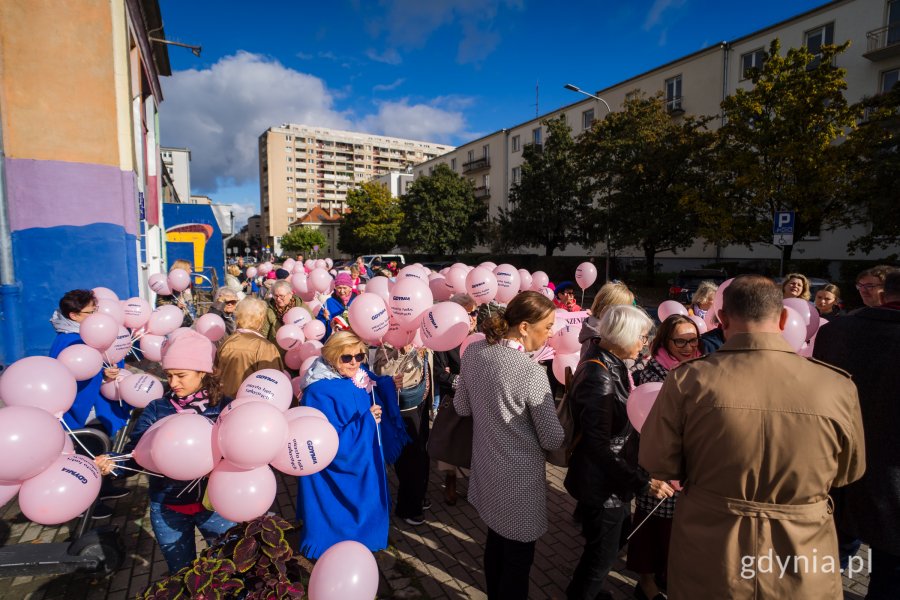 Uczestnicy Marszu Różowej Wstążki z różowymi balonami w rękach przed Teatrem Miejskim w Gdyni 