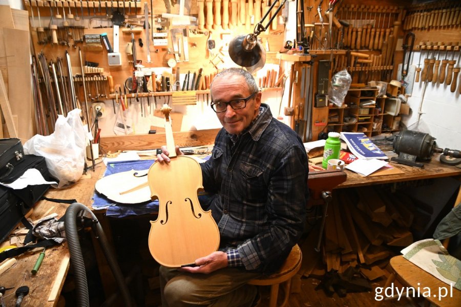 Pan Tomasz Grzeszczak, lutnik i opiekun szkolnych instrumentów trzyma w rękach skrzypce
