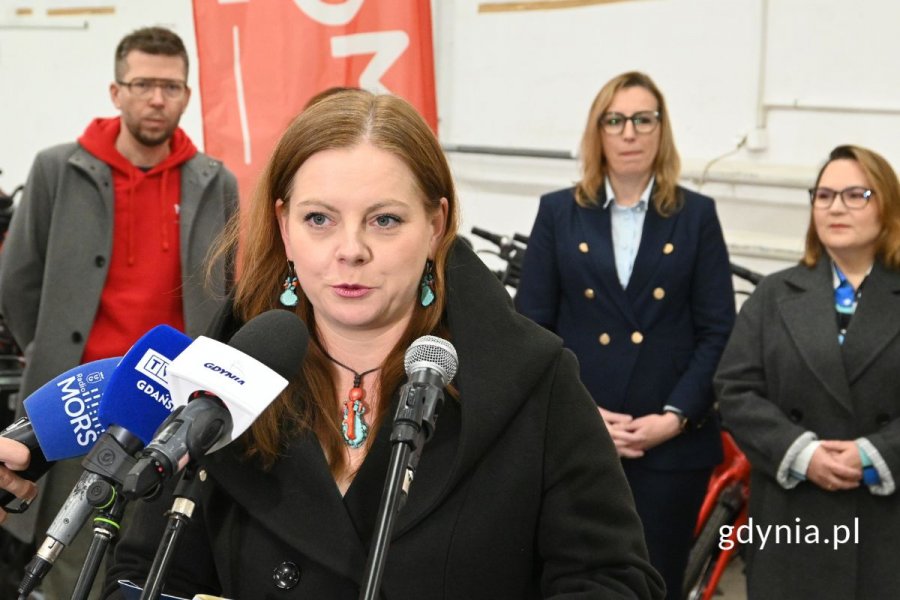 Kobieta mówiąca do kilku ustawionych obok siebie mikrofonów