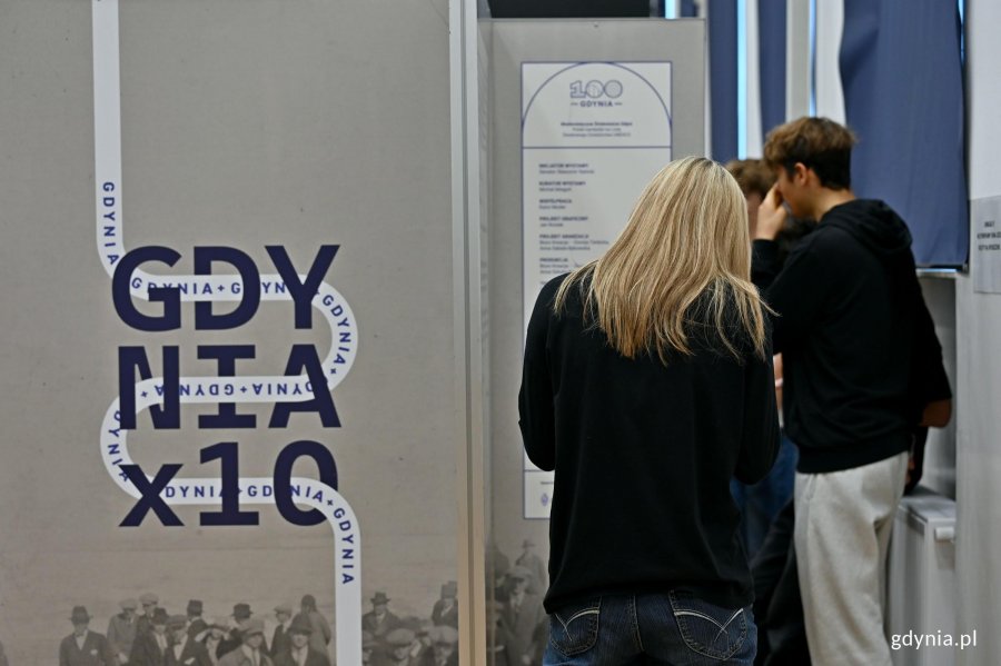 Uczniowie II LO zwiedzający wystawę &bdquo;Gdynia x 10&rdquo; w auli szkoły 