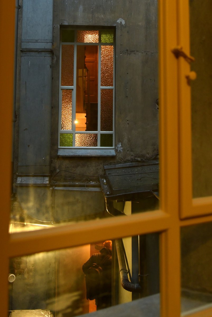 Widok na kamienicę przez stare drewniane okno.