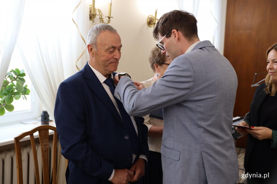 Mężczyzna w garniturze wręcza medal innemu mężczyźnie