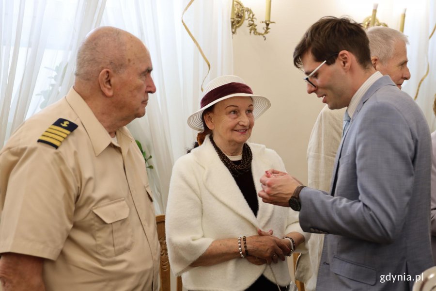 Para: mężczyna z mundurze, kobieta w kapeluszu i mężczyzna w garniturze z medalem