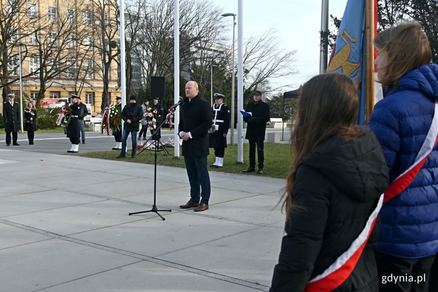 Na drugim planie, przy mikrofonie: wiceprezydent Gdyni Bartosz Bartoszewicz wygłasza okolicznościowe przemówienie podczas uroczystości z okazji 80. rocznicy utworzenia Armii Krajowej. Na pierwszym planie poczet sztandarowy zlozony z uczniów SP nr 26 w Gdyni // fot. Magdalena Czernek