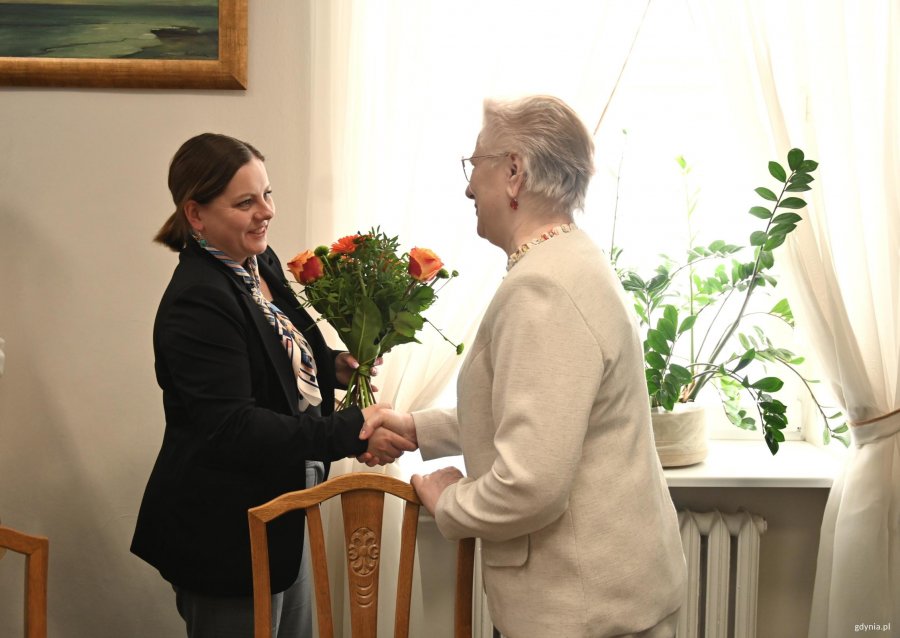 Kobieta w ciemnej marynarce ściska dłoń kobiety w białej marynarce