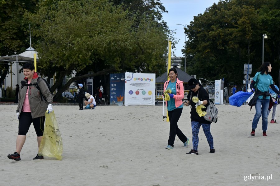 Grupa wolontariuszy na gdyńskiej plaży - biorą udział w akcji „Bałtycka Odyseja”. W rękach mają kolorowe worki i chwytaki // fot. Magdalena Czernek