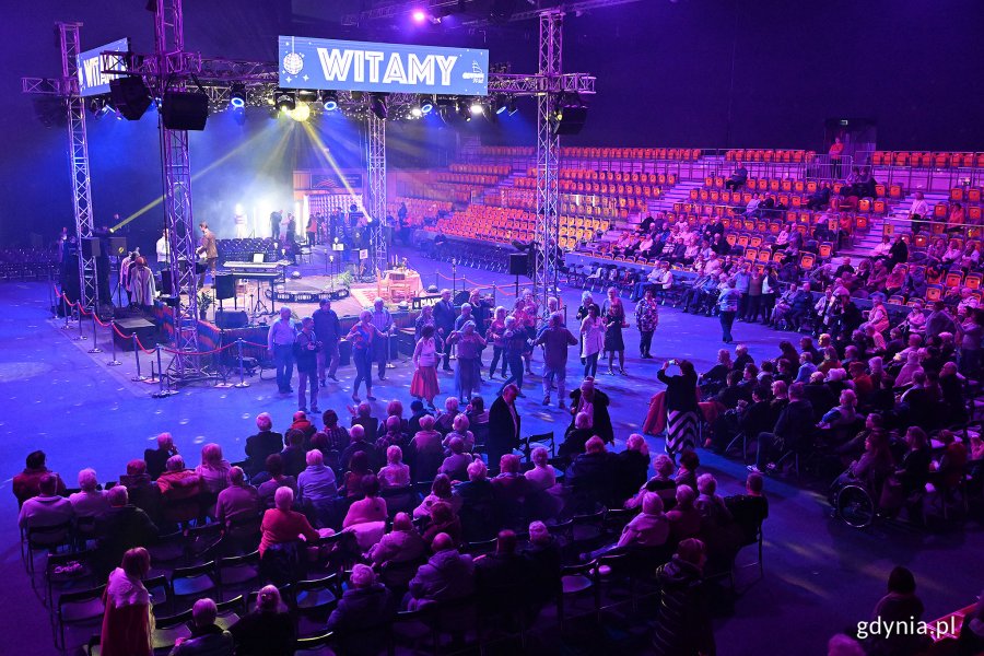 Hala Polsat Plus Arena, ludzie na trybunach i krzesełkach, na środku podświetlona scena