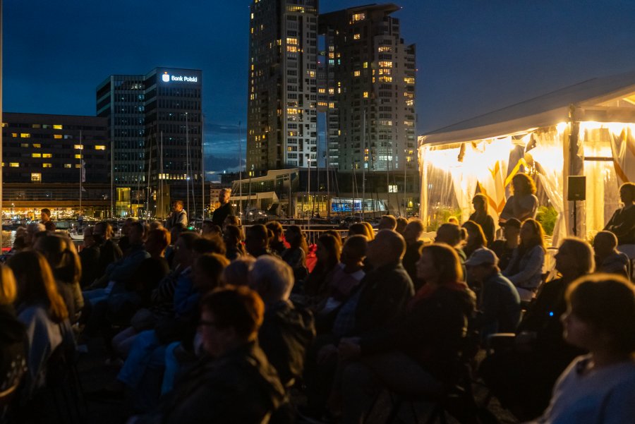 Widzowie zgromadzeni na pokazie spektaklu „Kopakonan – opowieść o kobiecie foce”, który można zobaczyć przy pomniku Tadeusza Wendy w Marina Yacht Parku w ramach festiwalu „Pociąg do Miasta”. W tle budynek Sea Towers // fot. Anna Rezulak