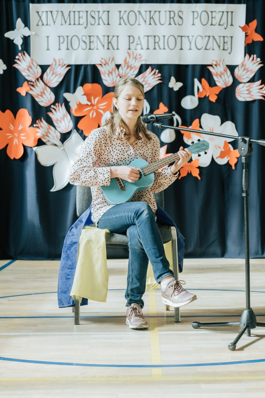 Dziewczynka z gitarą na scenie podczas Miejskiego Konkursu Poezji i Piosenki Patriotycznej