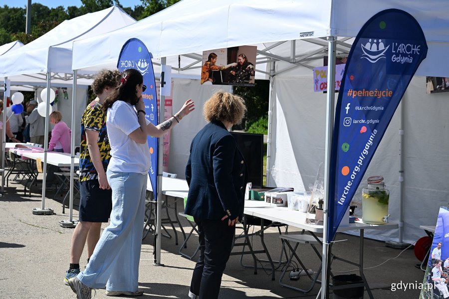 Grupa ludzi przy stoisku fundacji L'Arche podczas Gdyńskiego Pikniku Pozarządowego