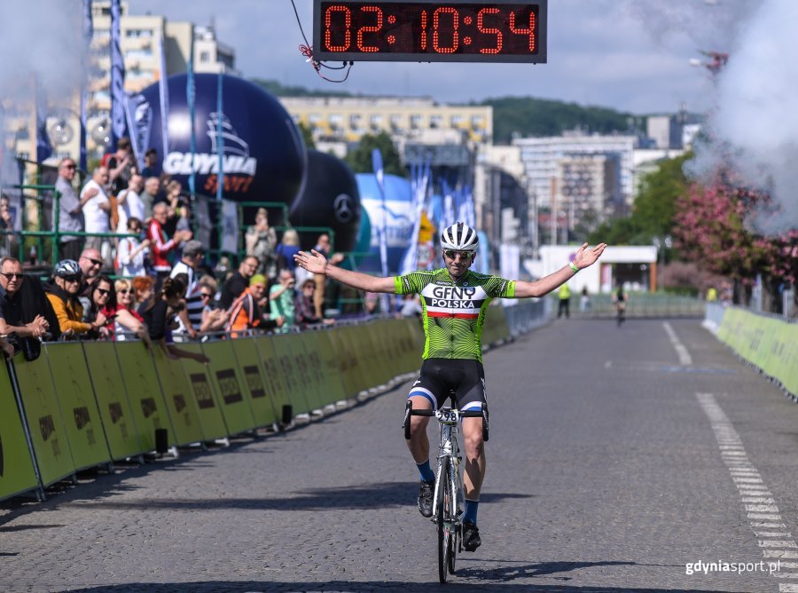 Kolarz wjeżdżający na metę podczas wyścigu Gran Fondo Gdynia 2018. W tle widoczne są zegar odliczający czas oraz balon z napisem "Gdynia".