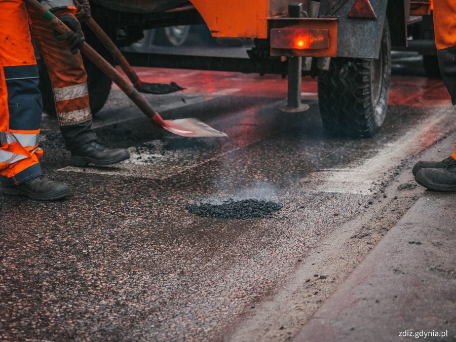 trwa  naprawa ubytku w nawierzchni, widoczna naprawa metodą na zimno