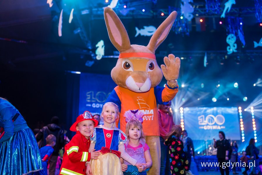 Troje dzieci w kostiumach w towarzystwie maskotki-zająca z Gdyńskiego Centrum Sportu