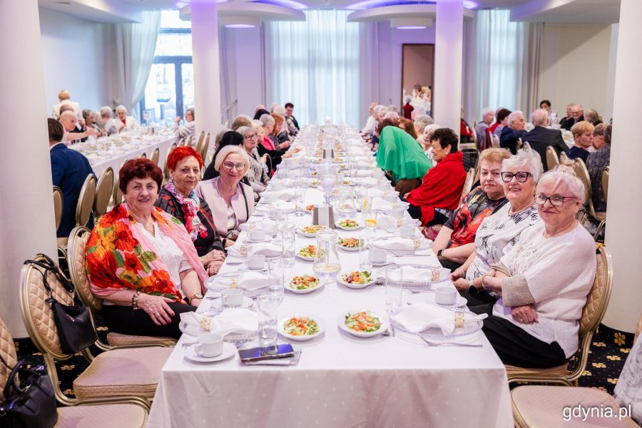 Grupa senior&oacute;w siedzi przy elegancko zastawionym stole