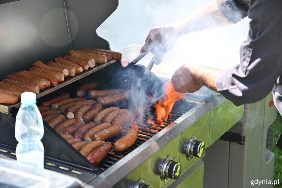 Płonący ogień pod kiełbasą na grillu