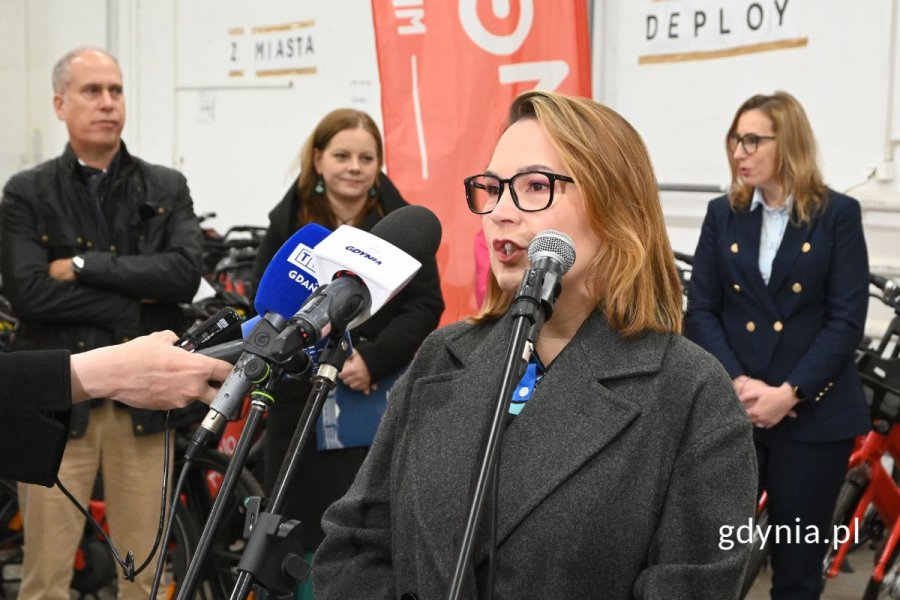 Kobieta mówiąca do kilku ustawionych obok siebie mikrofonów