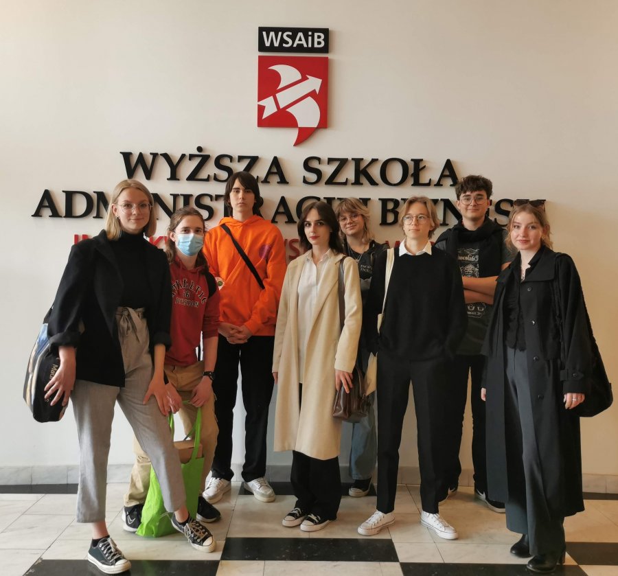 Uczniowie w togach na tle logo WSAiB