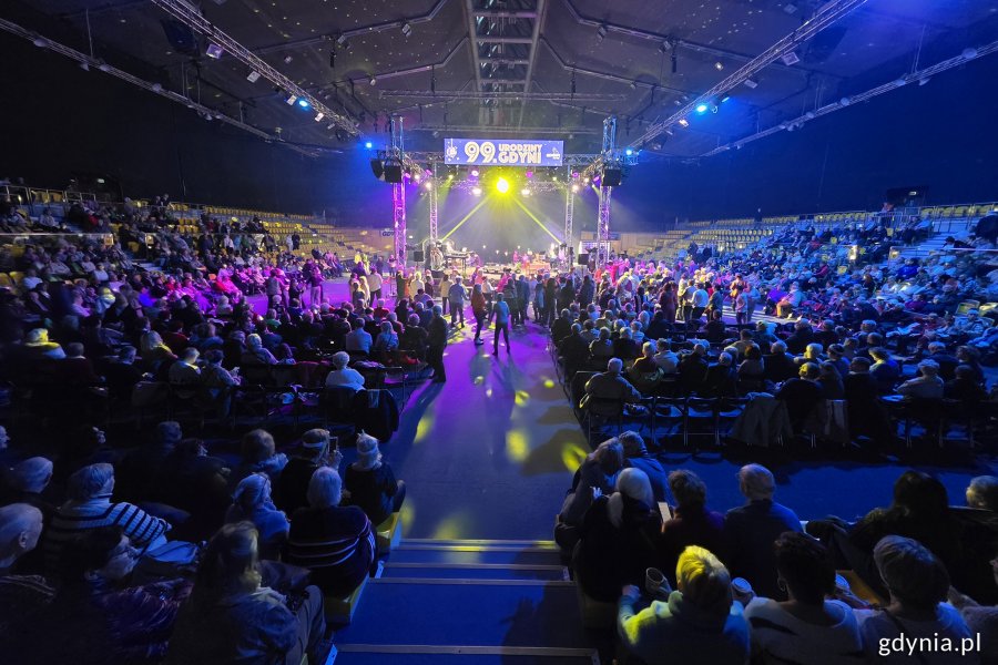 Hala Polsat Plus Arena Gdynia, widownia pełna ludzi, scena, niebieskie światło, kolorowe oświetlenie, grupa seniorów tańczy