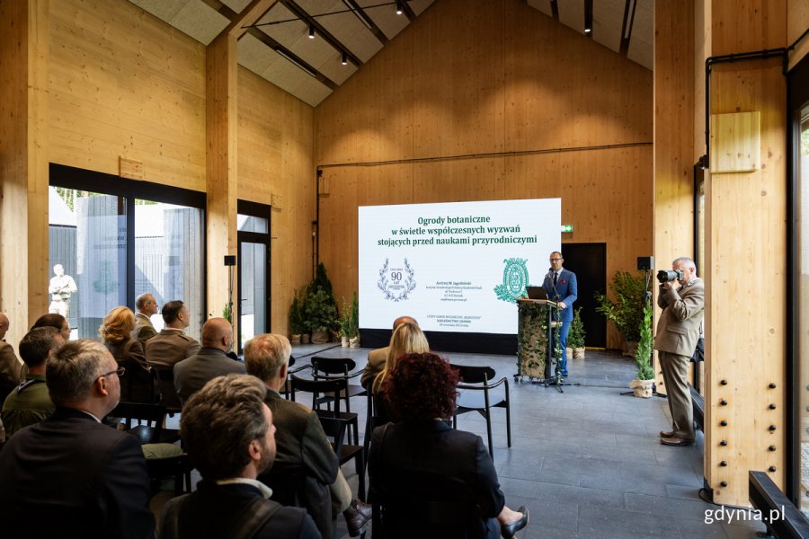 Konferencja w sali drewnianego, nowoczesnego budynku.