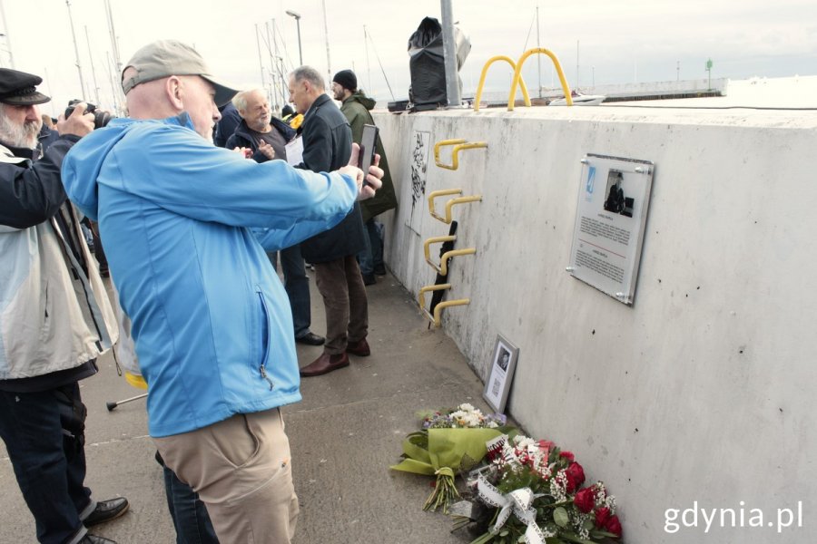 Ludzie robią zdjęcia tablicy kapitana Andrzeja Drapelli w gdyńskiej alei Żeglarstwa Polskiego