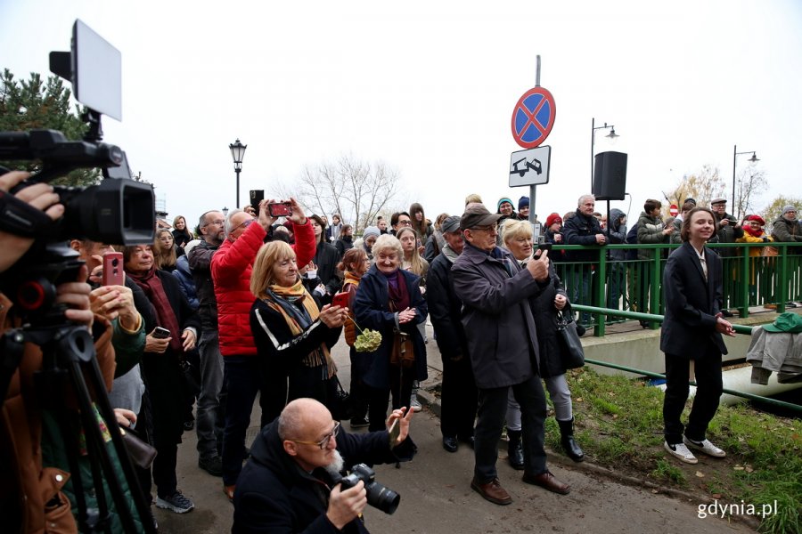 Ludzie zebrani na uroczystości odsłonięcia tablicy z nazwą ulicy.