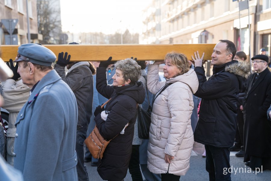 Uczestnicy Gdyńskiej Drogi Krzyżowej niosący krzyż. Wśród nich radny Dawid Biernacik