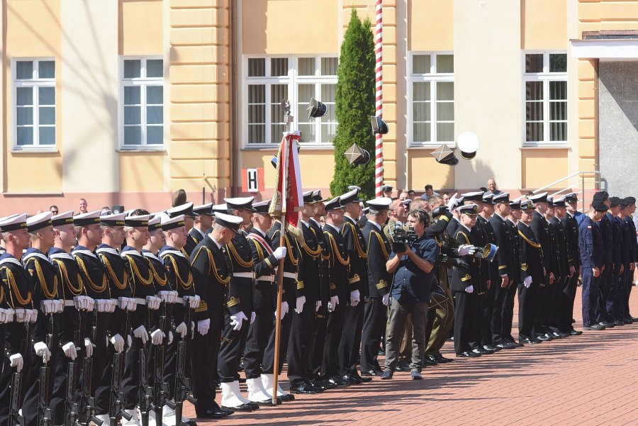 Uroczysta promocja oficerska w Akademii Marynarki Wojennej w Gdyni. Żołnierze stoją ustawieni w rzędzie. Po prawej stronie absolwenci rzucają do góry czapki // fot. Krzysztof Miłosz