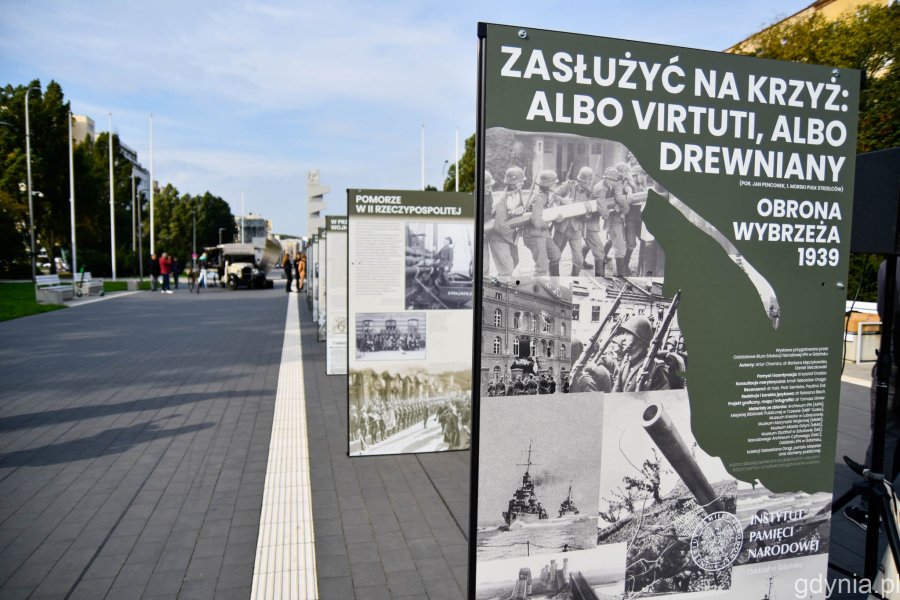 Wystawa „Zasłużyć na krzyż: albo Virtuti, albo drewniany. Obrona Wybrzeża 1939” na skwerze Kościuszki. Ustawione w rzędzie plansze stoją na chodniku. W tle pomnik Polski Morskiej // fot. Paweł Kukla