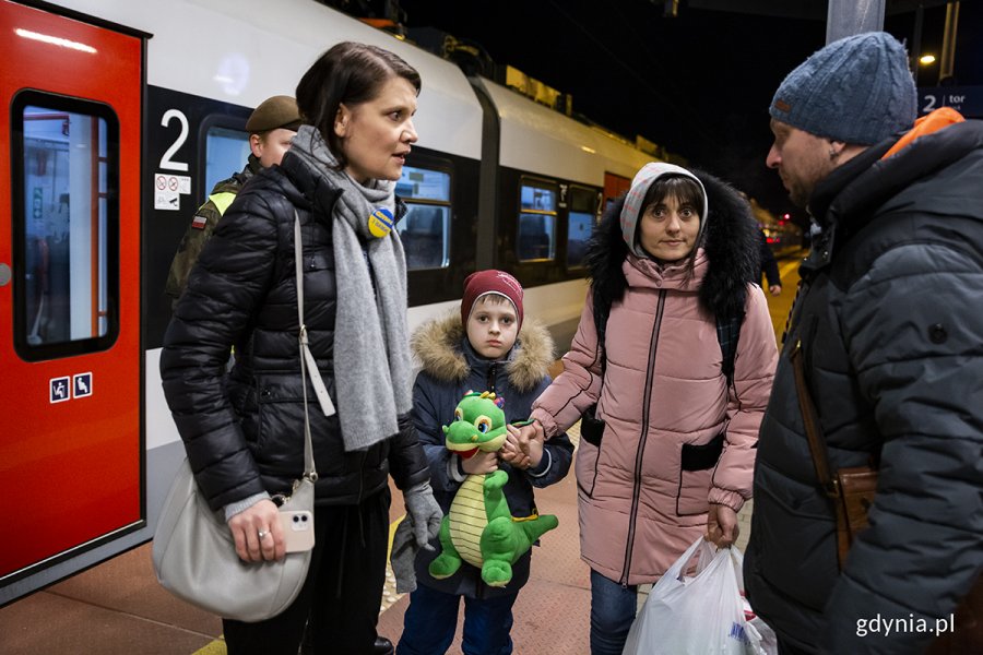 Wiceprezydent Gdyni Katarzyna Gruszecka Spychała rozmawia z uchodźcami z Ukrainy na peronie kolejowym.